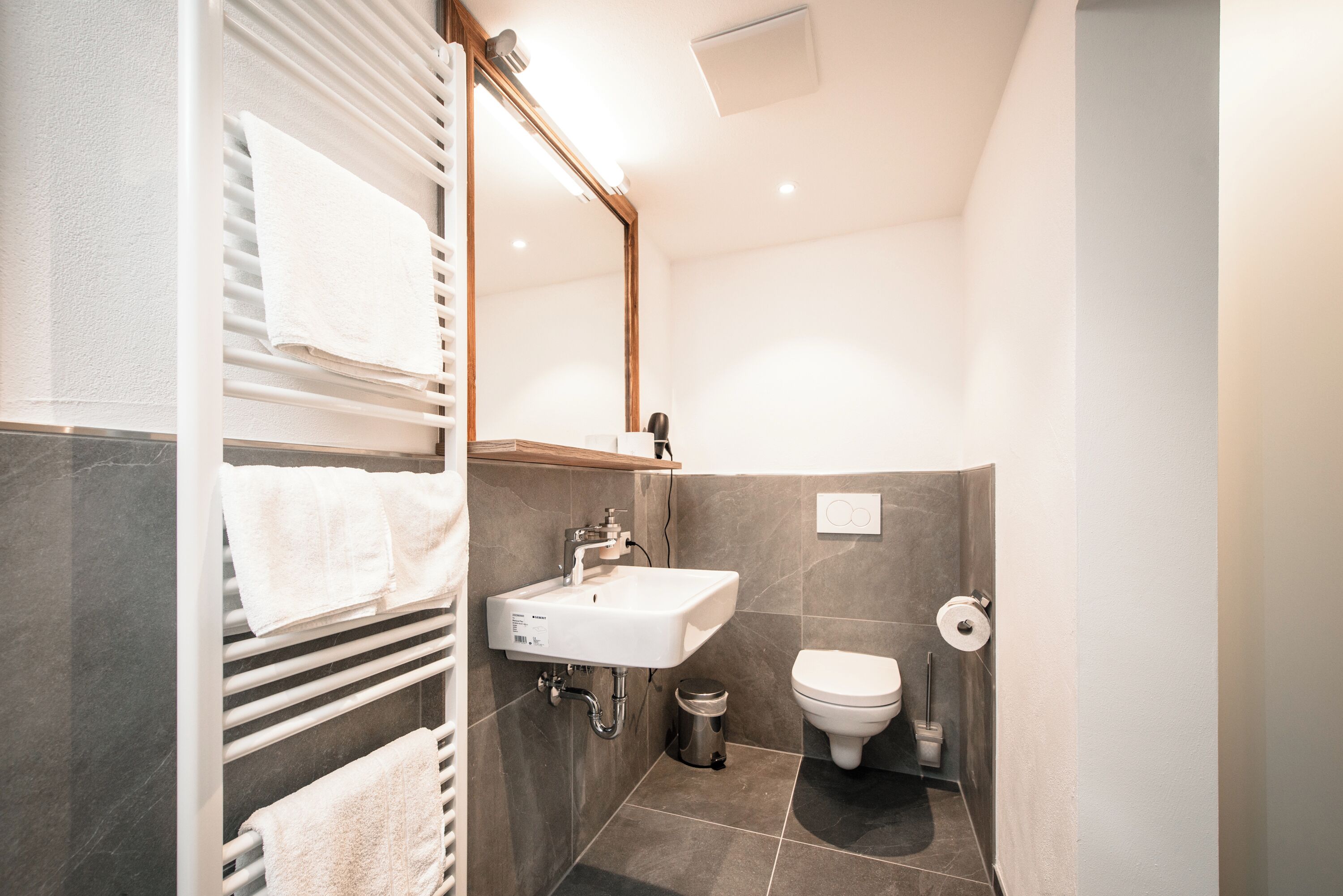 Une salle de bain moderne avec un lavabo blanc, des toilettes et un porte-serviettes.