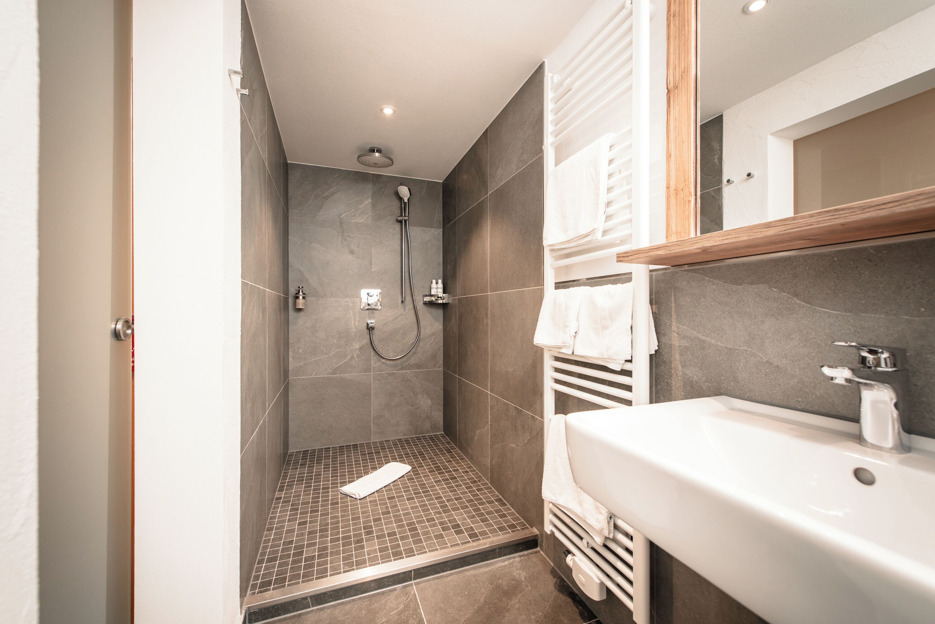 Un baño moderno con ducha, lavamanos y espejo.