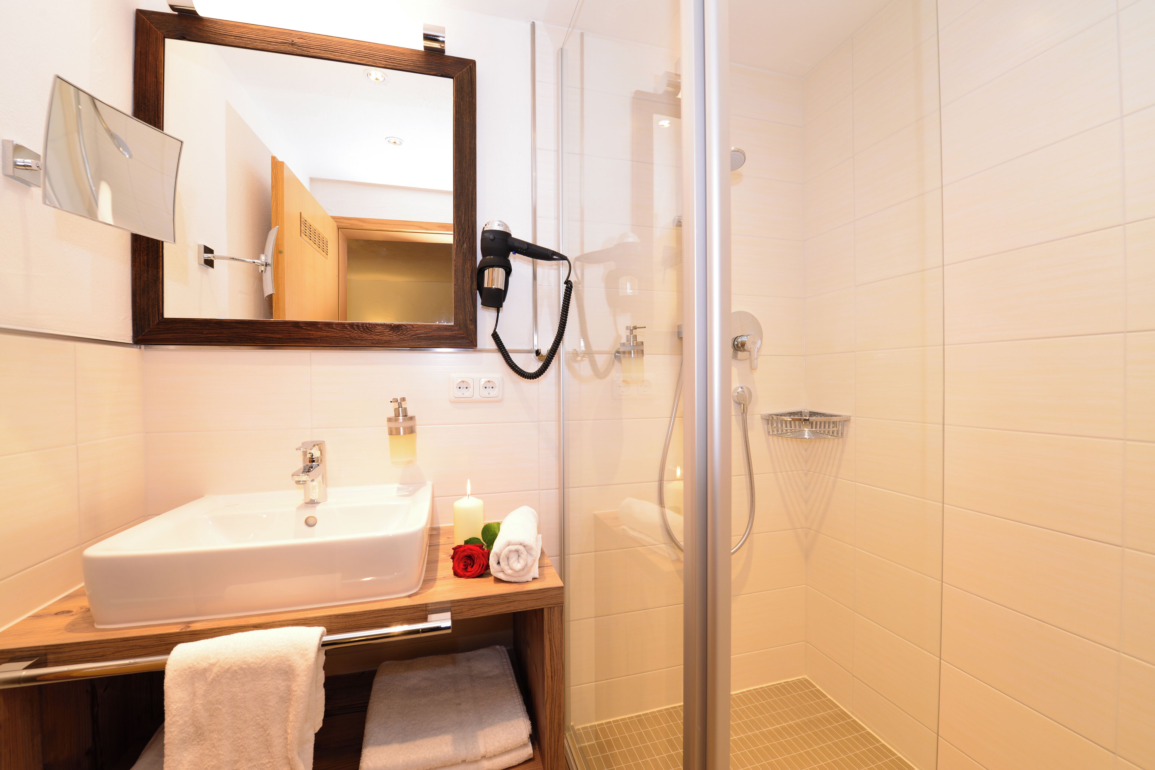 A bathroom with a sink, mirror, and shower.