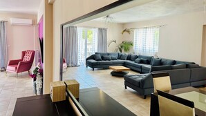 A modern living room with a sectional sofa, a red armchair, a coffee table, and a TV. - Airfenos - Luxury home in the Athens Riviera, Greece. (Anavissos)