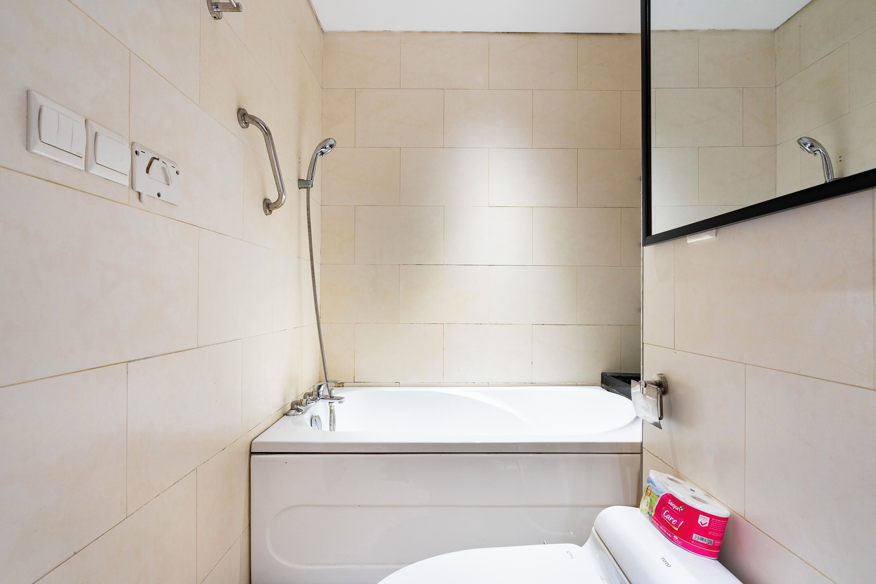 Un baño con bañera, inodoro y barra de apoyo.