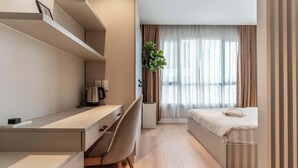 Une chambre d’hôtel moderne équipée d’un lit, d’un bureau avec une chaise, d’une machine à café et d’une plante en pot.