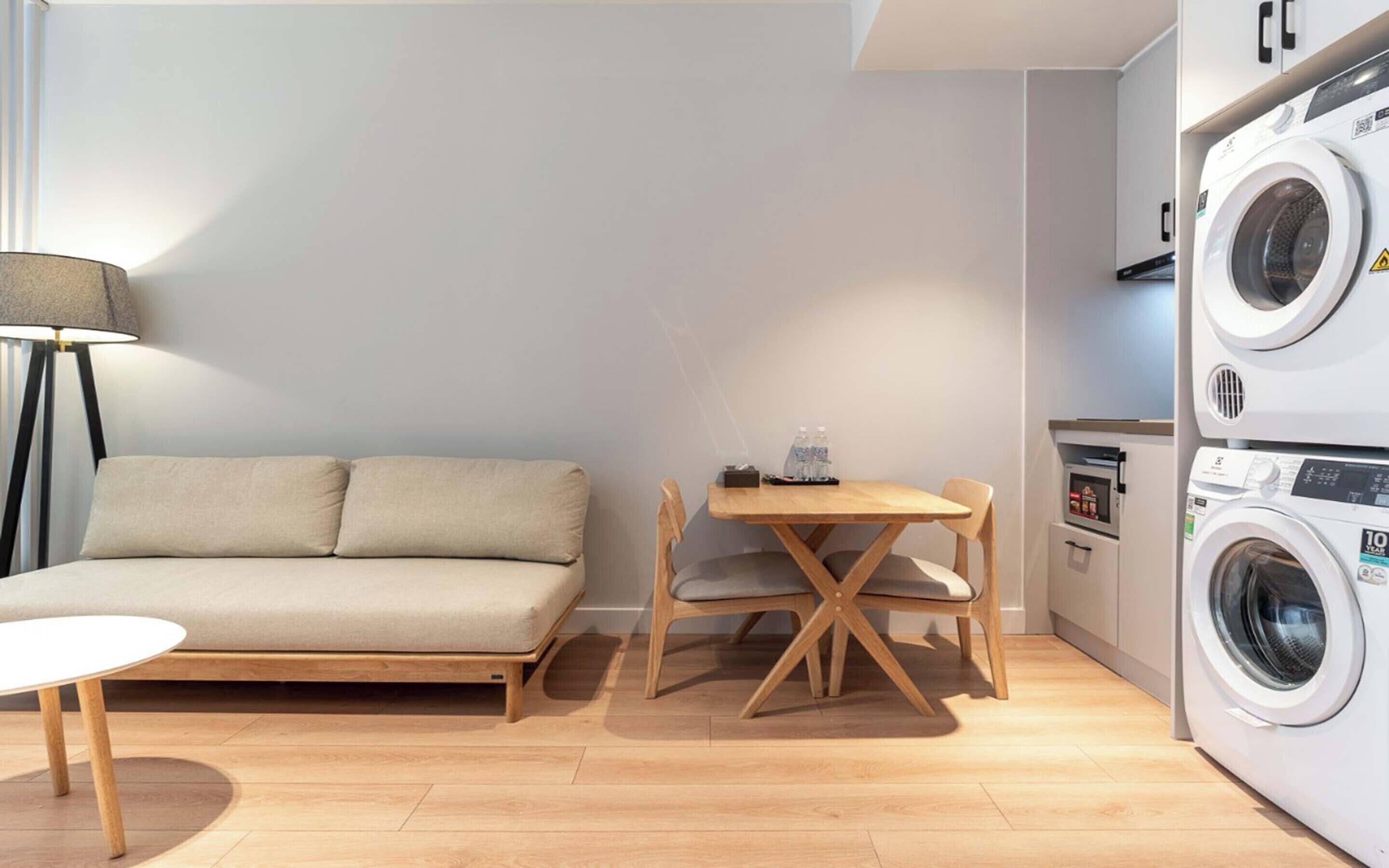 A compact living space with a sofa, a small table, a lamp, and a washing machine.