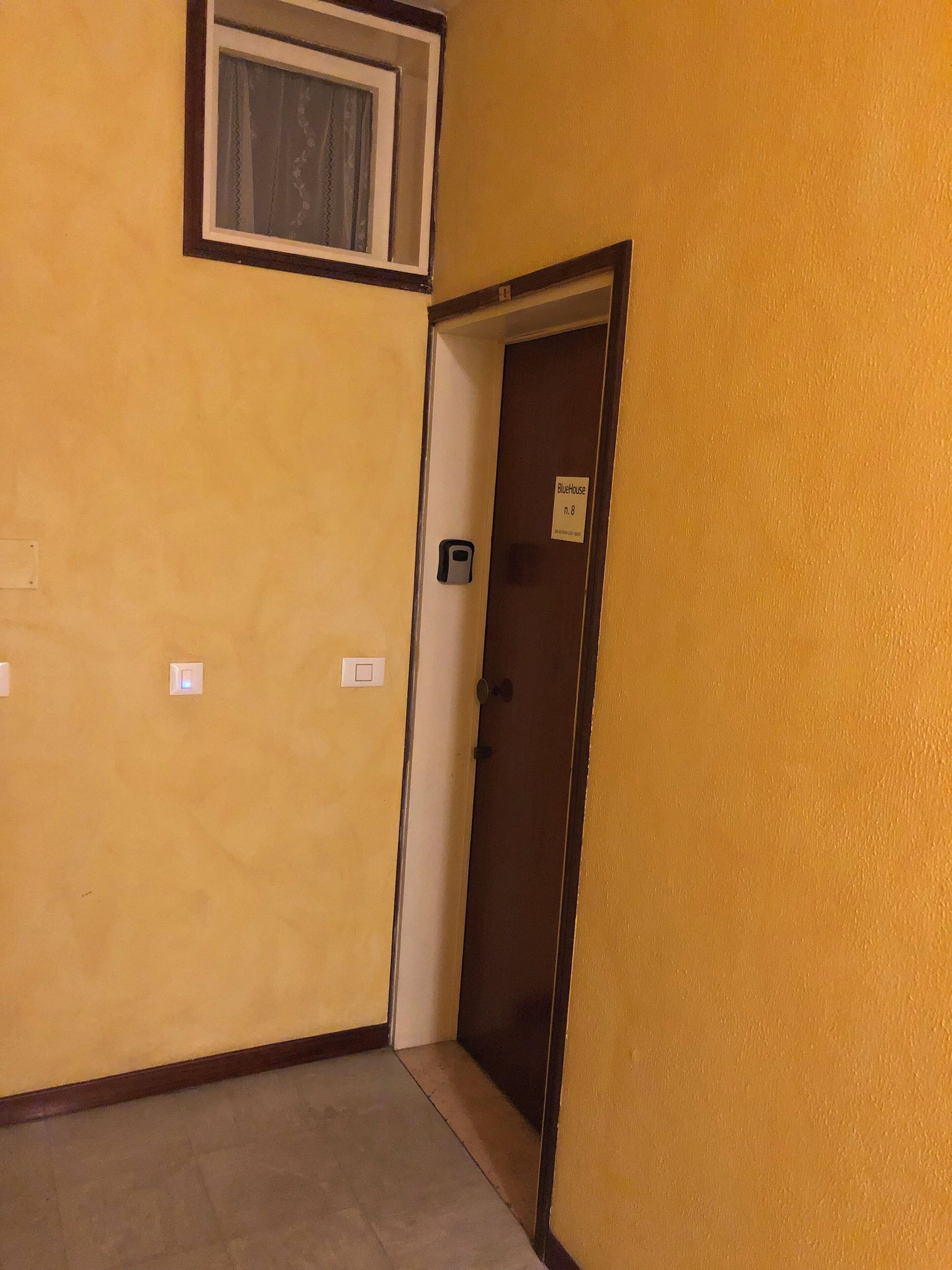 A hallway with a door labeled "BlueHouse n.8" and a small window above it.