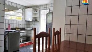 Une cuisine avec des meubles blancs, un réfrigérateur et une table à manger avec des chaises.