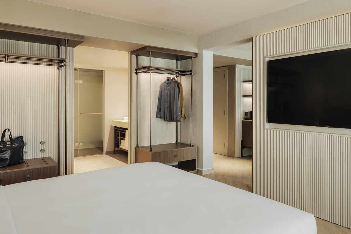 Una habitación de hotel con cama, armario, televisor y baño.