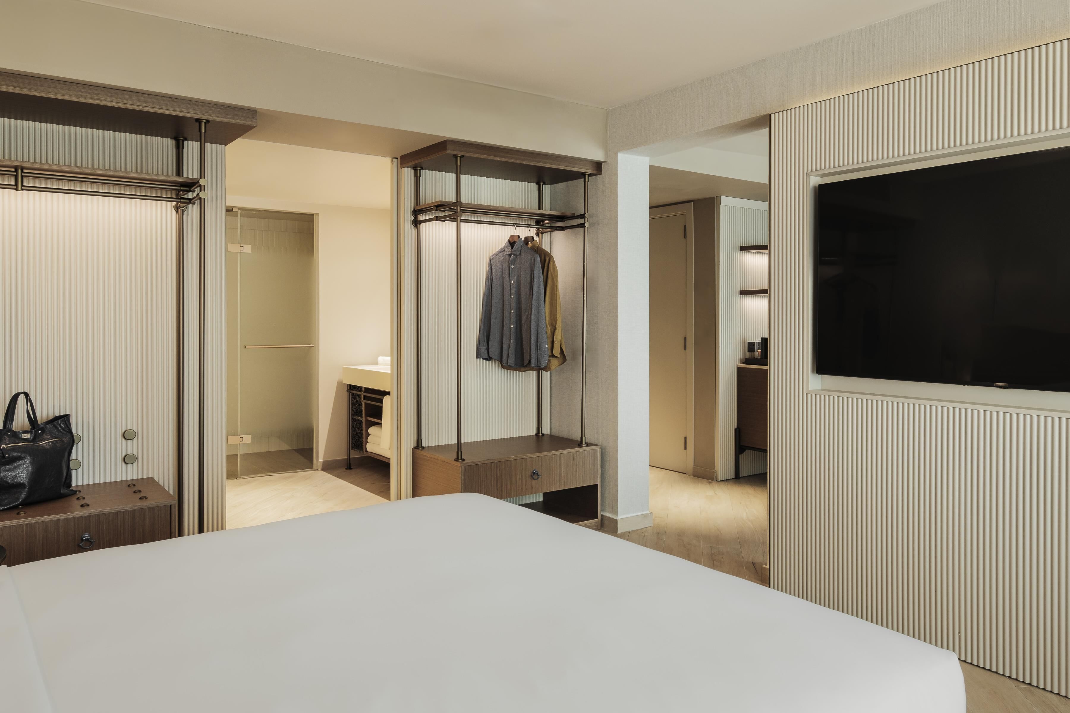 A hotel room with a bed, a wardrobe, a television, and a bathroom.