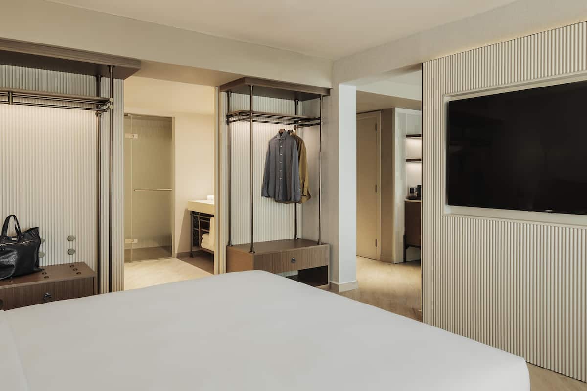 A hotel room with a bed, a wardrobe, a television, and a bathroom.