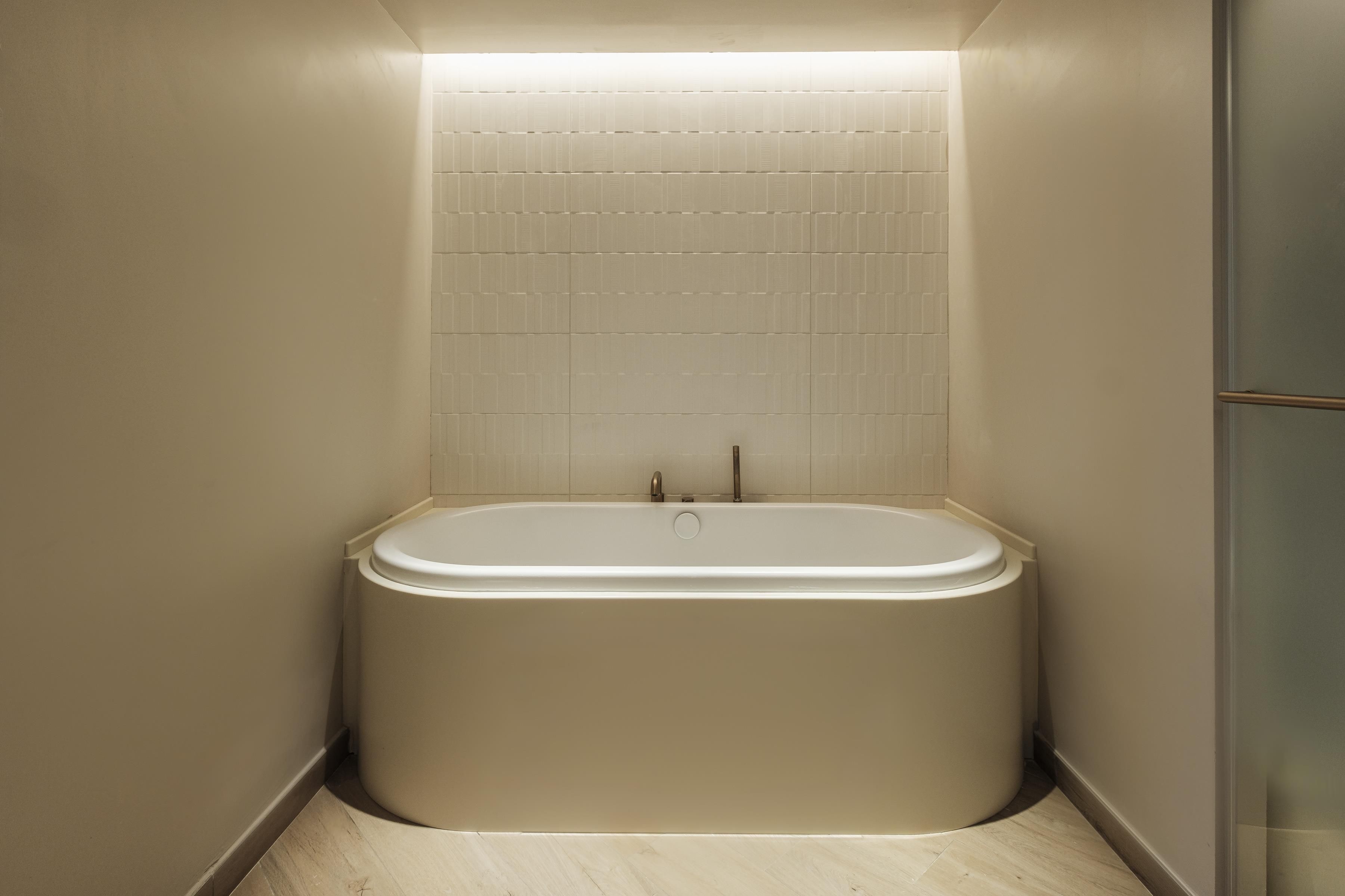 Une salle de bain moderne avec une baignoire sur pieds, des murs carrelés et un plancher en bois.