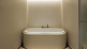 Une salle de bain moderne avec une baignoire sur pieds, des murs carrelés et un plancher en bois.