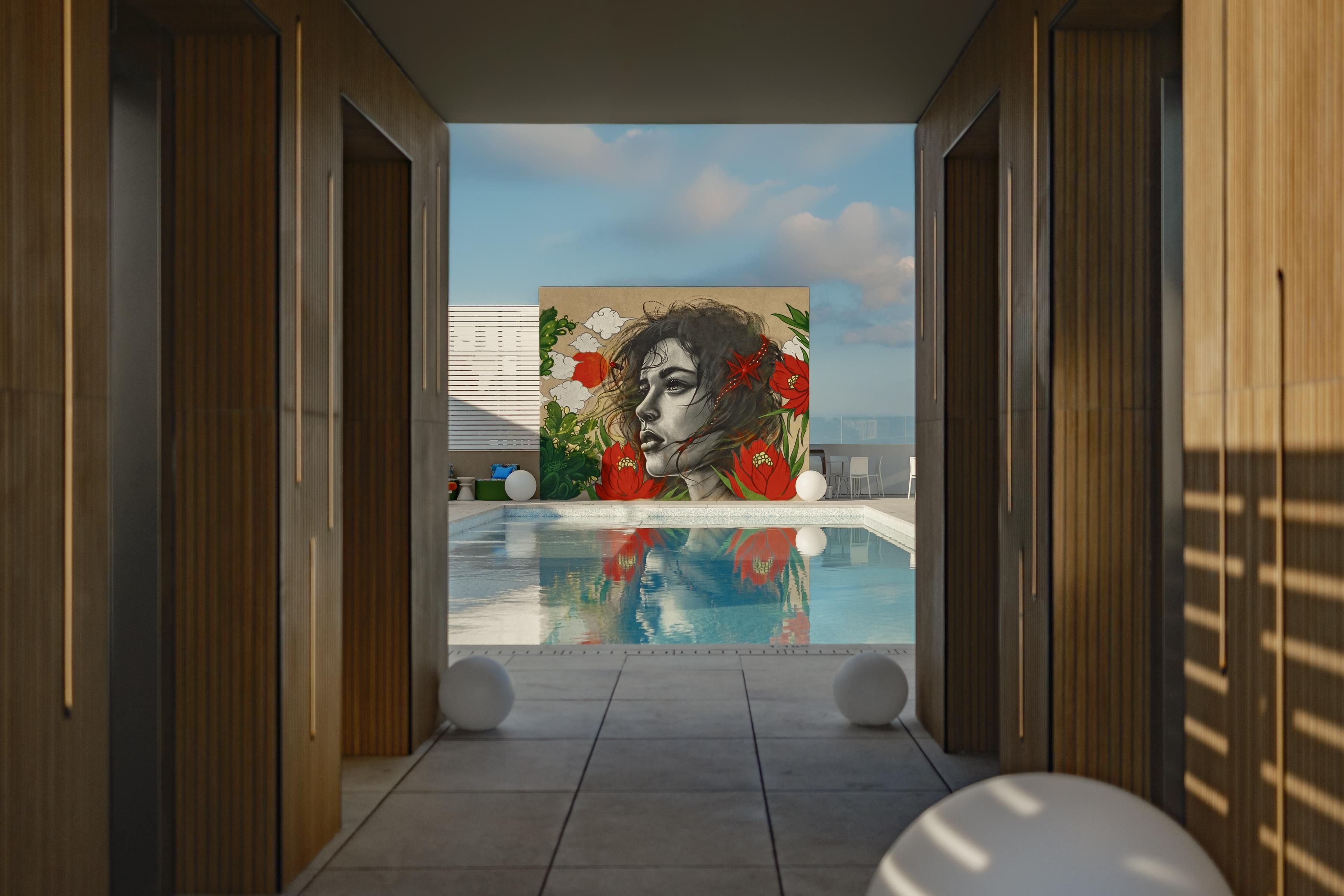 Un área de piscina interior moderna con un mural, paneles de madera y vistas despejadas al cielo.