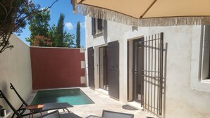 Une terrasse avec une table et des chaises, une petite piscine et un espace salon abrité.