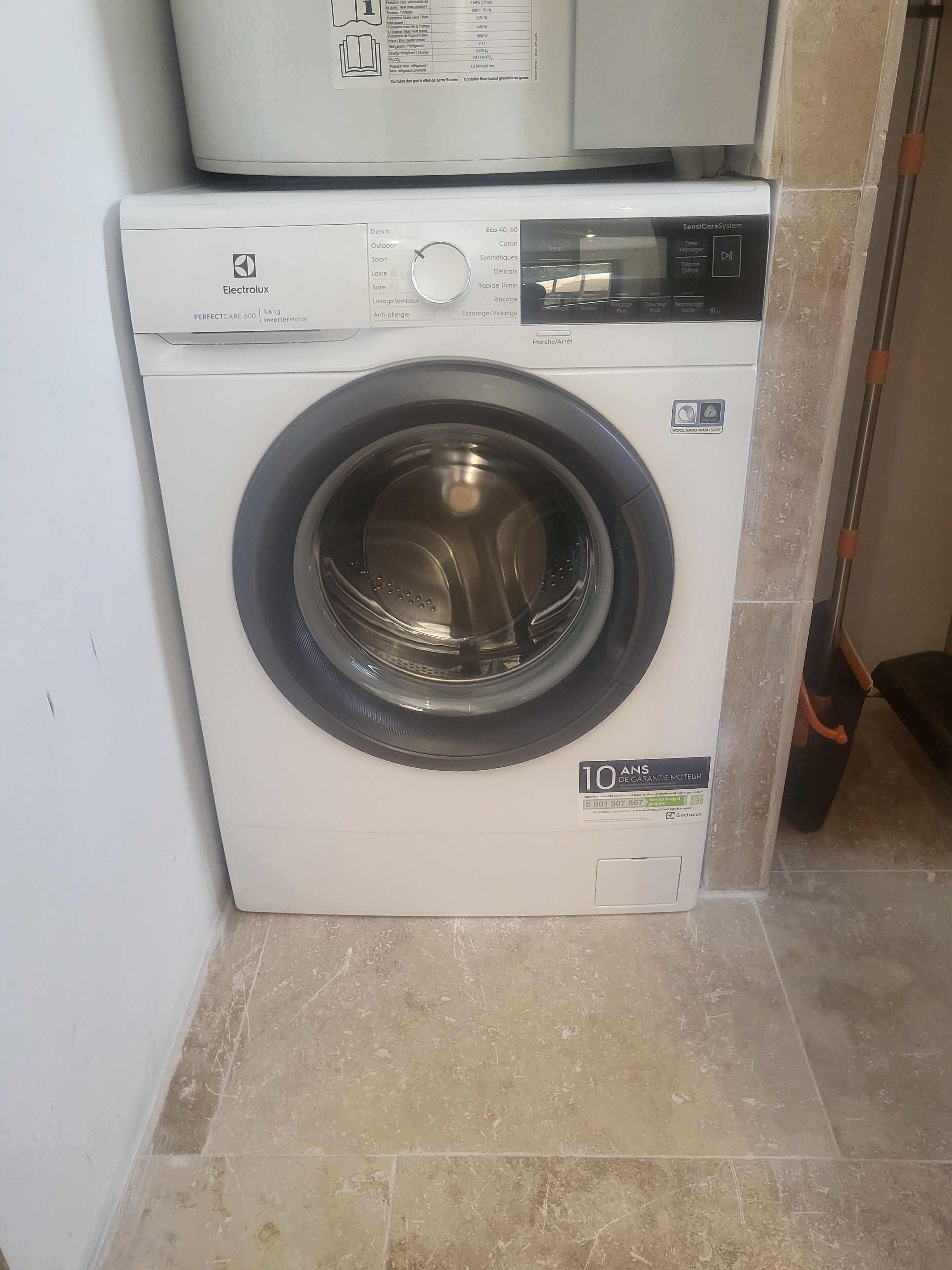 A front-loading Electrolux washing machine with a digital display and a hand wash safety symbol.