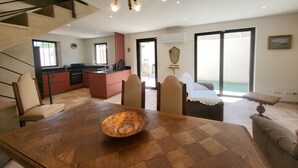 Un vaste espace de vie comprenant une table à manger en bois, un canapé et une cuisine en arrière-plan.