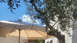 Un espace patio avec une piscine, des sièges d’extérieur et un grand parasol.