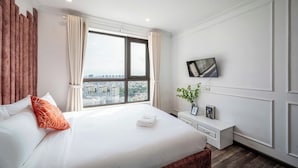 Ein Hotelzimmer mit einem großen Bett, einem an der Wand befestigten Fernseher und einem Fenster mit Vorhängen.