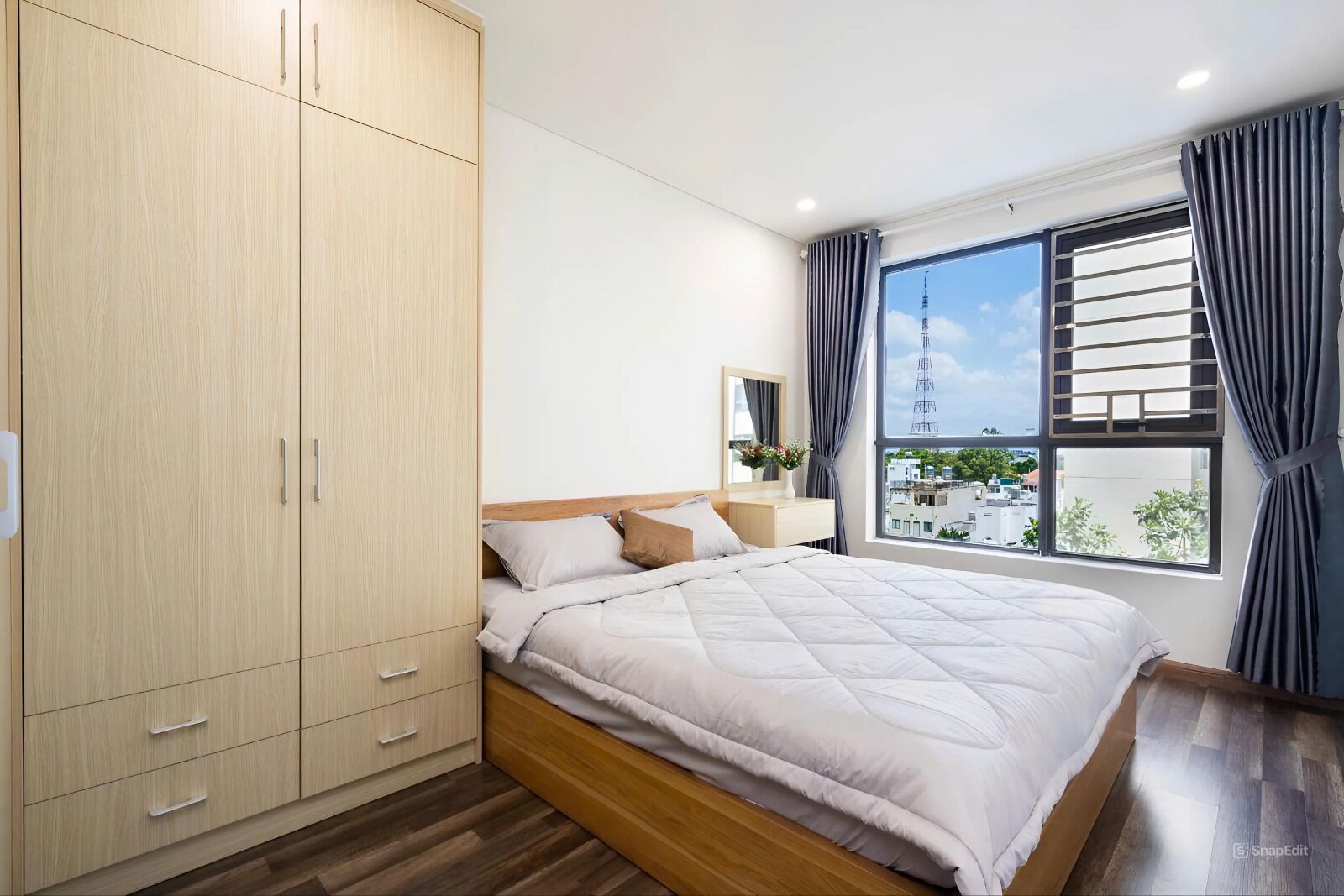 A bedroom with a bed, a wardrobe, a nightstand, and a window with curtains.