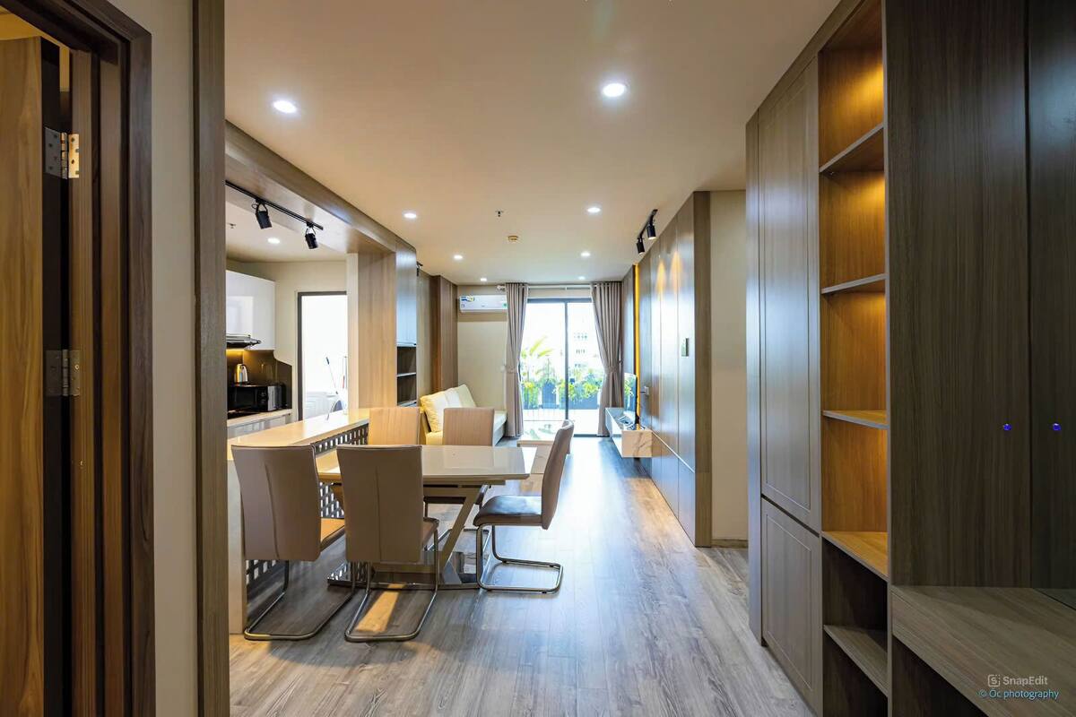 A modern kitchen with a dining area, wooden cabinets, and a large window.