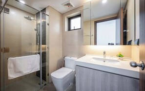Ein modernes Badezimmer mit einer Duschkabine, einer Toilette und einem Waschtisch mit Waschbecken und Spiegel.