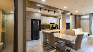 Eine moderne Küche mit Einbaukühlschrank, ein Essbereich mit Tisch und Stühlen sowie ein Sofa im Wohnbereich.