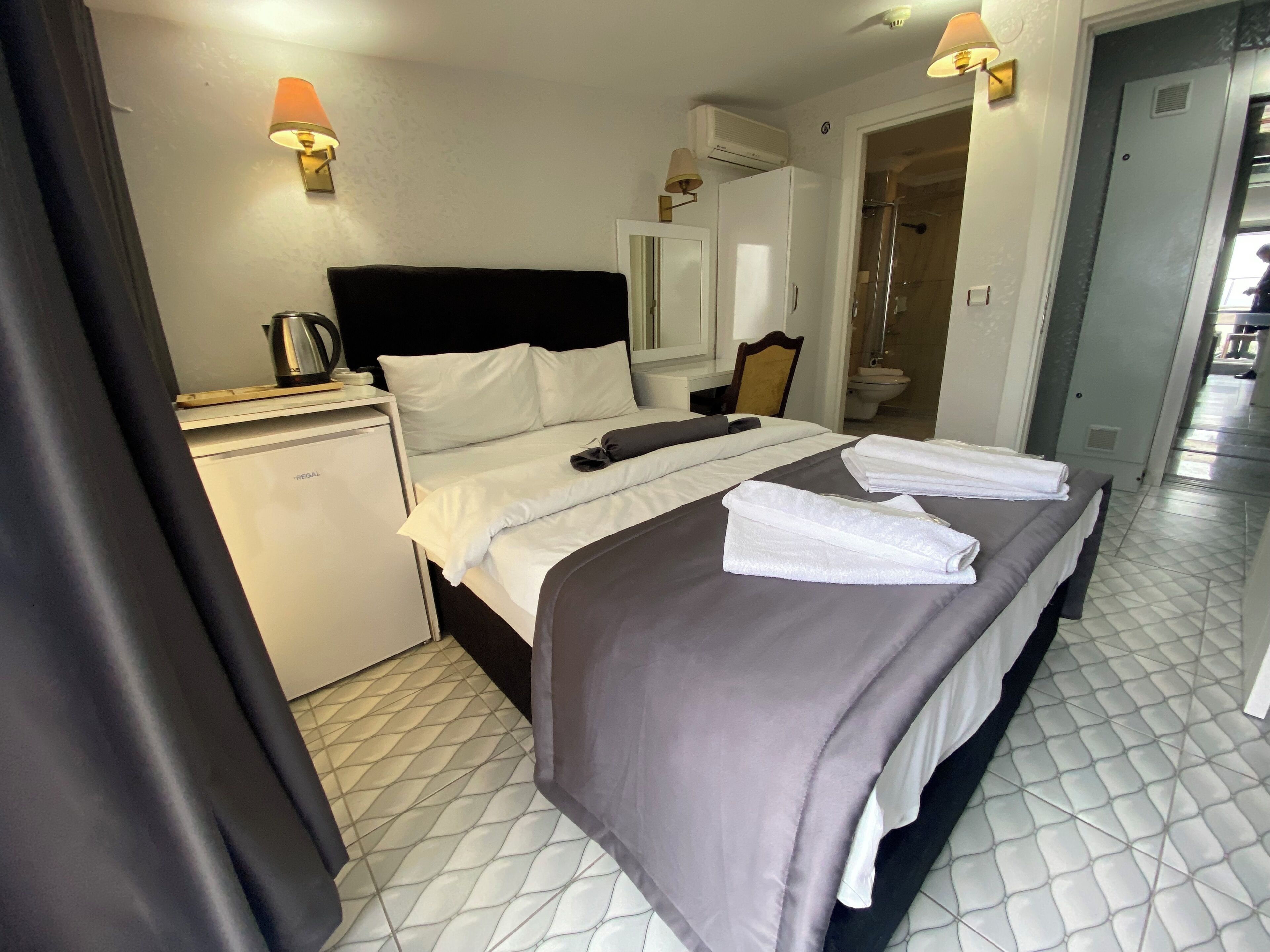 Ein Hotelzimmer mit Bett, Nachttisch, Spiegel, Dusche und Toilette.