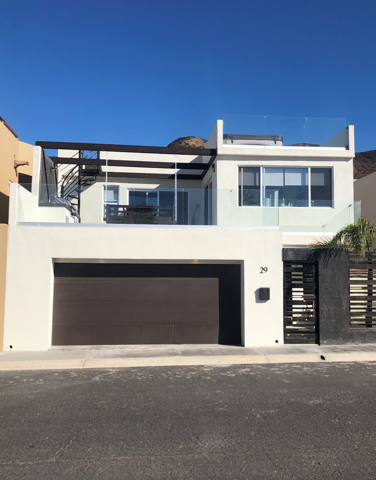 Een modern huis met twee verdiepingen, een garage, grote ramen en een balkon.