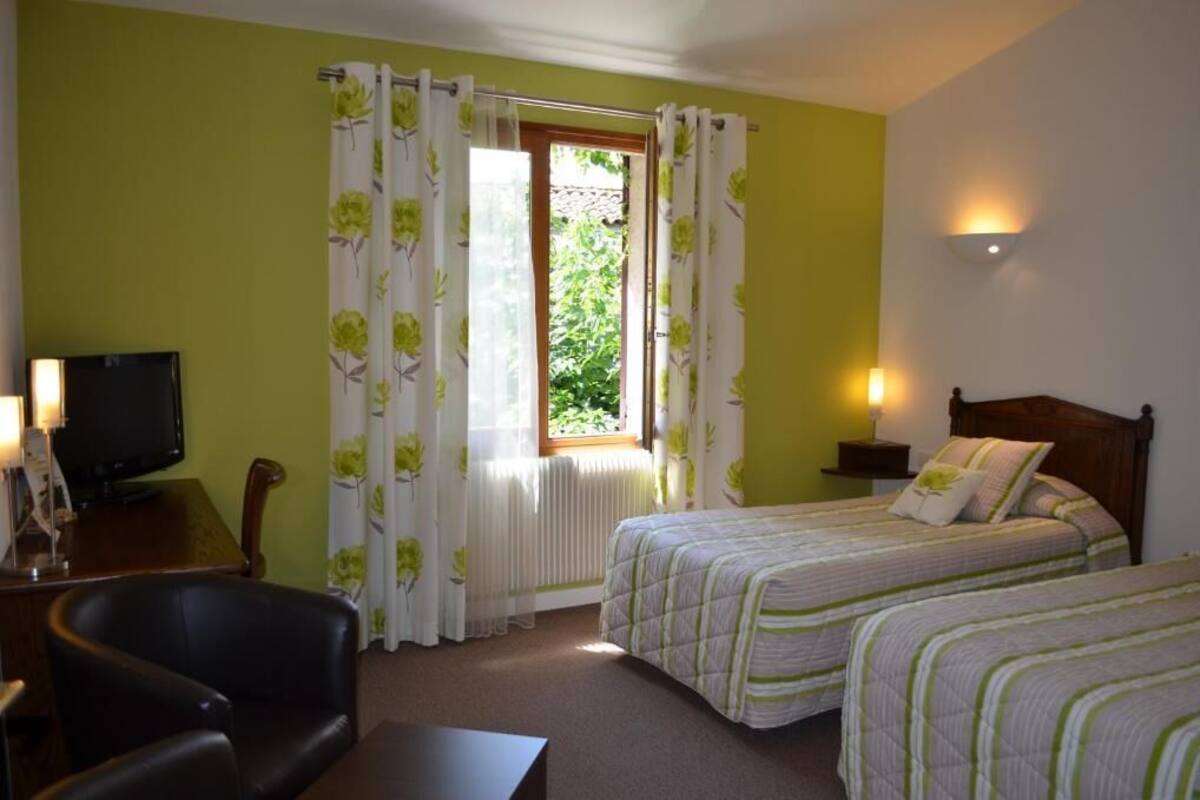 Een hotelkamer met twee bedden, een televisie, een stoel en een raam met gordijnen.