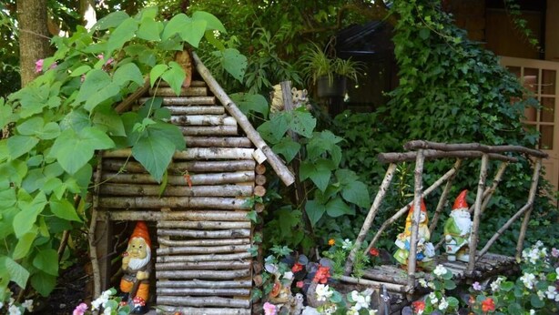Un jardin avec une petite maison en bois où habite un gnome et une balançoire en bois.