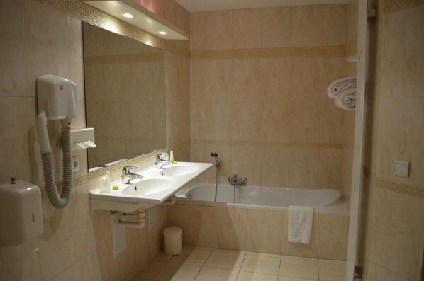A bathroom with two sinks, a mirror, a hairdryer, a shower, and a towel rack.