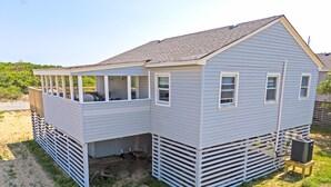 A two-story house with a covered porch and a small attached garage. - Cottage Close To Beach and abuts the Wright Brother Memorial (Kill Devil Hills)