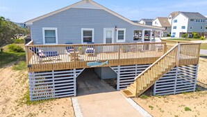A beach house with a wooden deck, outdoor seating, and a staircase leading to the entrance. - Cottage Close To Beach and abuts the Wright Brother Memorial (Kill Devil Hills)