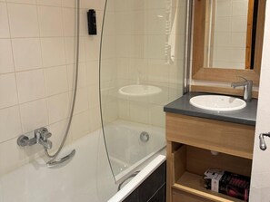 Ein modernes Badezimmer mit einer Duschkabine aus Glas, einer weißen Badewanne und einem Waschbecken mit Holzunterschrank.