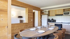 Una mesa de comedor de madera con sillas, una cocina con armarios de madera, un microondas y una estufa.