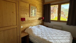 Una habitación con paneles de madera, una cama, un cuadro en la pared y una ventana con vista a edificios.