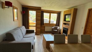 Una sala moderna con un sofá, una mesa de comedor de madera y una televisión.
