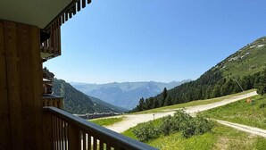 A balcony with a wooden railing overlooking a mountainous landscape. - Ski-in/ski-out & foot of the slopes, 3rd floor, view ski slopes, swimming pool, balcony, tv (La Plagne)