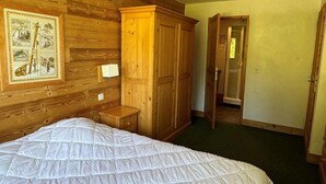A bedroom with a large bed, wooden wardrobe, and a framed picture on the wall. - Ski-in/ski-out & foot of the slopes, 3rd floor, view ski slopes, swimming pool, balcony, tv (La Plagne)