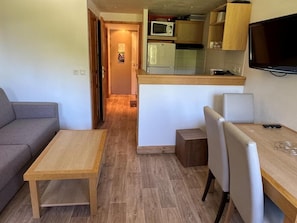 Un espacio habitable compacto con kitchenette, comedor y sofá.