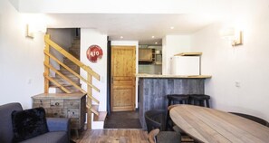 Un espacio habitable pequeño con una escalera de madera, una zona de cocina y una mesa de comedor.