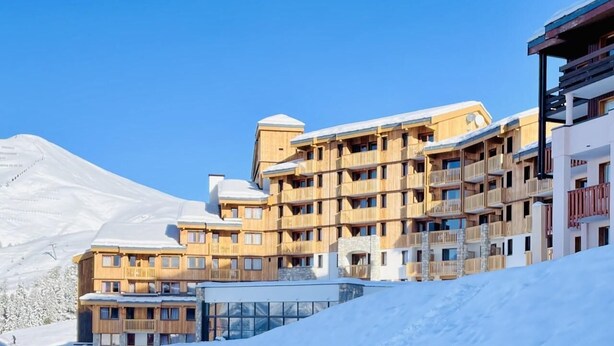 A multi-story wooden building with balconies, surrounded by snow-covered mountains. - 7th floor, view ski slopes, swimming pool, balcony, tv, ski locker, 41m², La Plagne (La Plagne)