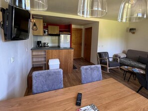 Un espacio habitable compacto con comedor, kitchenette y zona de estar.