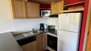 A compact kitchen with wooden cabinets, a microwave, a toaster, a coffee maker, a sink, and a refrigerator. - 7th floor, view ski slopes, swimming pool, balcony, tv, ski locker, 41m², La Plagne (La Plagne)