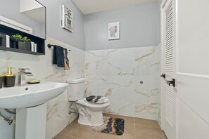 Bathroom features a white sink, toilet, and marble backsplash.