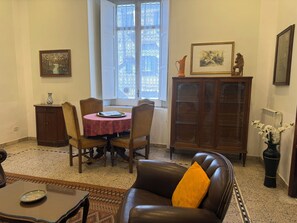 Un comedor con una mesa redonda, sillas, un armario y un sofá con cojín.