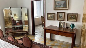 A hotel room with a bed, a wooden desk, a chair, a mirror, and framed pictures on the wall. - Historical Maison des Artistes in Aristocratic XVI Century Palace  (Napoli)