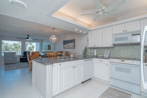A modern kitchen with white cabinets, a central island, a microwave, and an oven. - Beachfront 3BR Townhouse Not a Condo! Pet Friendly (Panama City Beach)