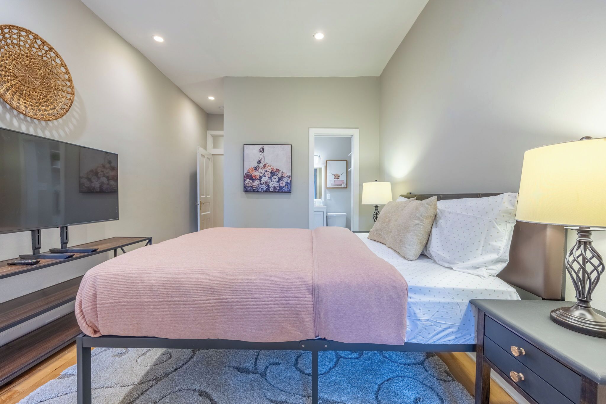 Una camera da letto moderna con un letto, un comodino, una lampada e un'opera d'arte appesa al muro.