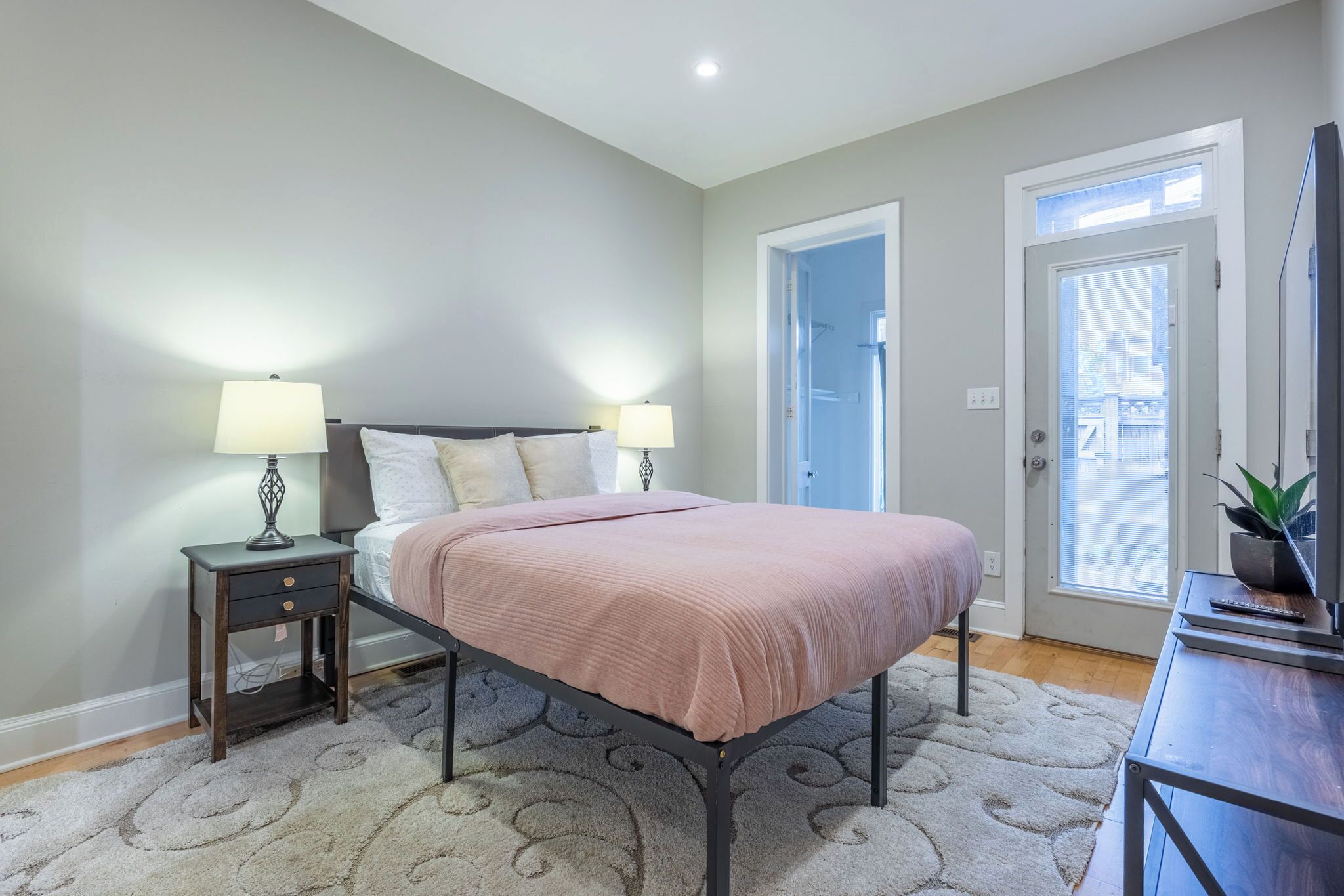 A bedroom with a bed, bedside tables, a door, and a window.