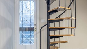 A spiral staircase with wooden steps and black railings, leading to an upper floor.