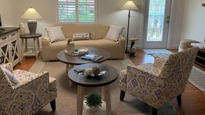 A living room with a sofa, two armchairs, a coffee table, a lamp, and a vase.